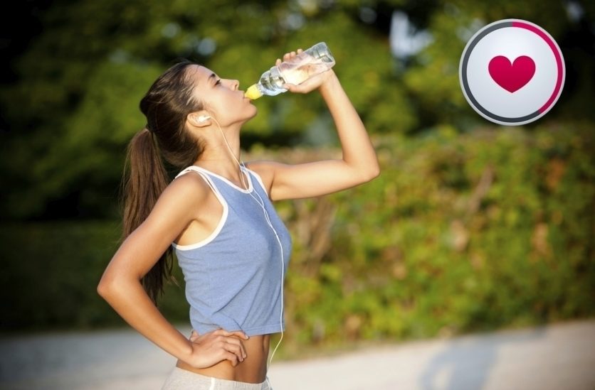 Slim young woman drinking water after training