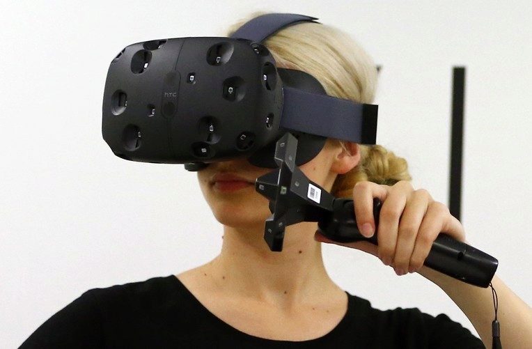 A woman checks a pair of Vive Virtual Reality goggles, produced by Taiwan’s HTC, during the Gamescom 2015 fair in Cologne