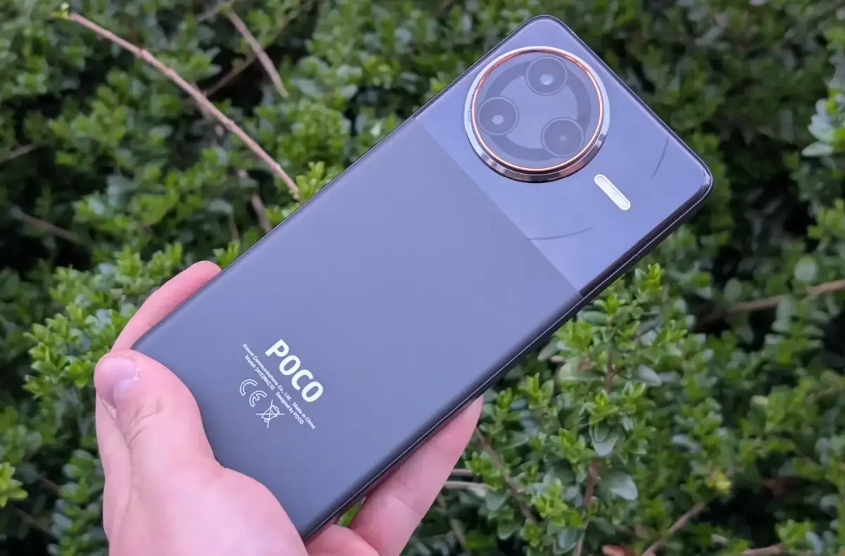 poco f7 ultra v ruce na pozadi s kerem