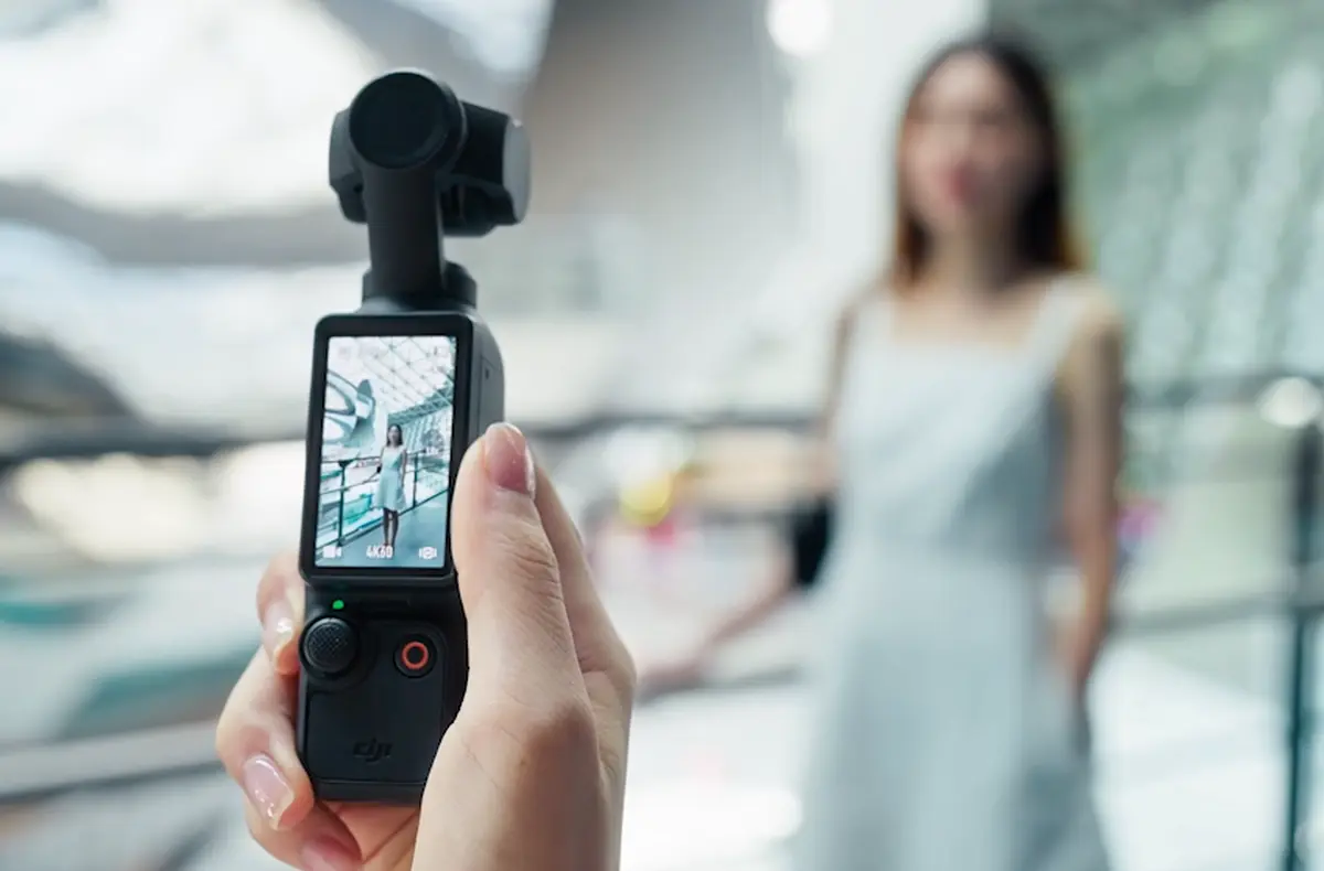 DJI Osmo Pocket 3 v ruce nahravajici zenu u zabradli